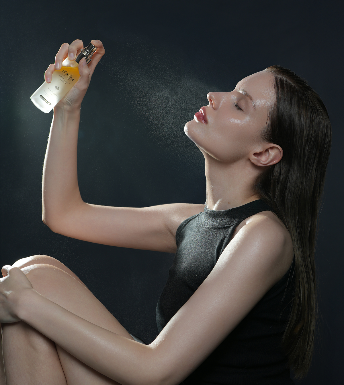 Woman misting face with d'Alba First Spray Serum